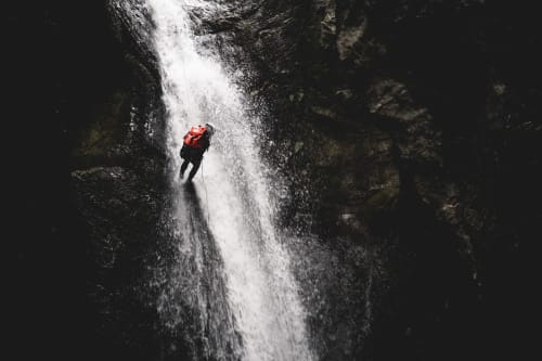 Person canyoning down waterfall near Ribeira Brava, Madeira adventure activity