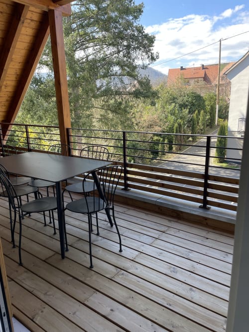 Terrasse en bois avec table à manger et chaises, vue panoramique sur les montagnes de l'appartement La clé des vignes à Ribeauvillé