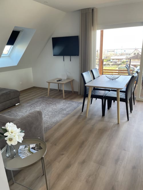 Séjour moderne avec TV, table en bois, canapé gris et terrasse vue jardin à La clé des vignes