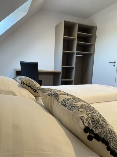 Coussins décor sur le lit de la chambre avec étagères et bureau à La clé des vignes, Ribeauvillé