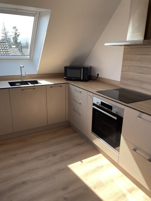 Cuisine moderne avec meubles clairs, four intégré et puits de lumière à La clé des vignes, Ribeauvillé
