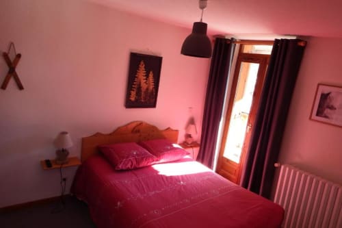 Bright pink bedroom with burgundy bedding, wooden door to garden, pendant lamp, and mountain view at Auberge du Pont de l'Alp