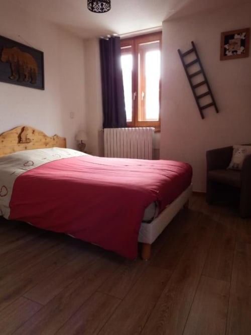 Cozy double room at Auberge du Pont de l'Alp with red bedding, wooden floors, mountain views, and garden access in Le