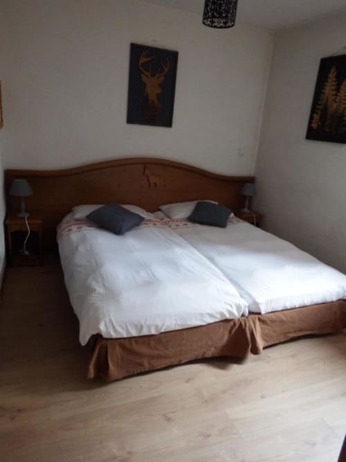 Chambre à l'Auberge du Pont de l'Alp avec lit en bois, literie blanche et œuvres animalières à Le Monêtier-les-Bains