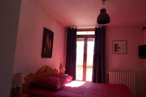 Chambre rose vif à l'Auberge du Pont de l'Alp au Monêtier-les-Bains avec lit double, portes-fenêtres et suspension moderne