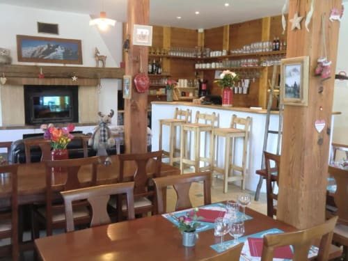 Salle à manger de l'Auberge du Pont de l'Alp avec mobilier en bois, cheminée, comptoir bar et décor alpin à Le Monêtier-les-Bains