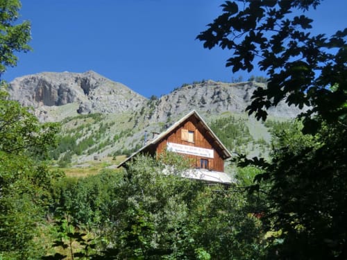 Auberge du Pont de l'Alp, lodge en bois niché dans une vallée alpine avec sommets montagneux et forêt, Le Monêtier-les-Bains