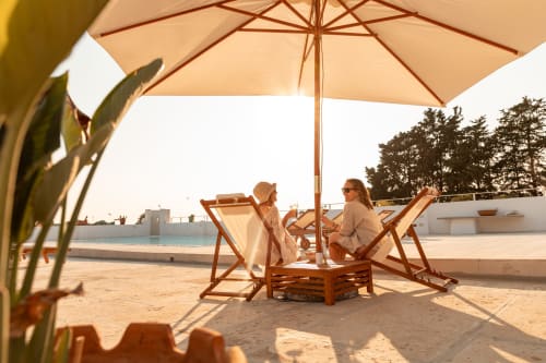 Due ospiti si rilassano sotto un ombrellone su lettini nella terrazza sul mare di Villa Ceci ad Andria, Italia