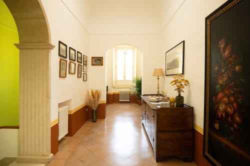 Elegante corridoio di Villa Ceci B&B ad Andria con pavimenti in cotto, opere d'arte classiche, mobili in legno e archi.