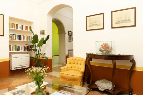 Villa Ceci BnB ad Andria - elegante living con poltrona gialla, mobili in legno, librerie e porta ad arco