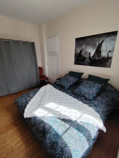 Chambre du gîte Skol In Normandy à Rouen avec literie à motifs, couverture blanche et décoration murale en forme de bateau