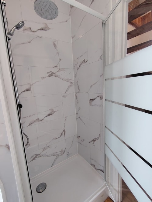 Salle de douche moderne avec carrelage effet marbre et pomme de douche pluie au gîte Skol In Normandy à Rouen