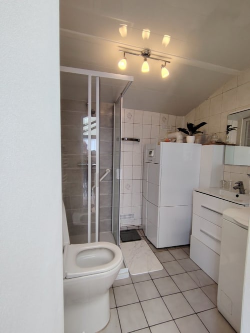 Salle de bains partagée du gîte Skol In Normandy à Rouen avec toilettes, douche, lavabo et éclairage chaleureux