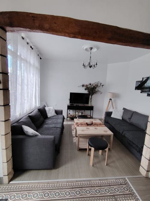 Séjour moderne avec deux canapés sombres, table basse en bois et téléviseur au gîte Skol, Rouen
