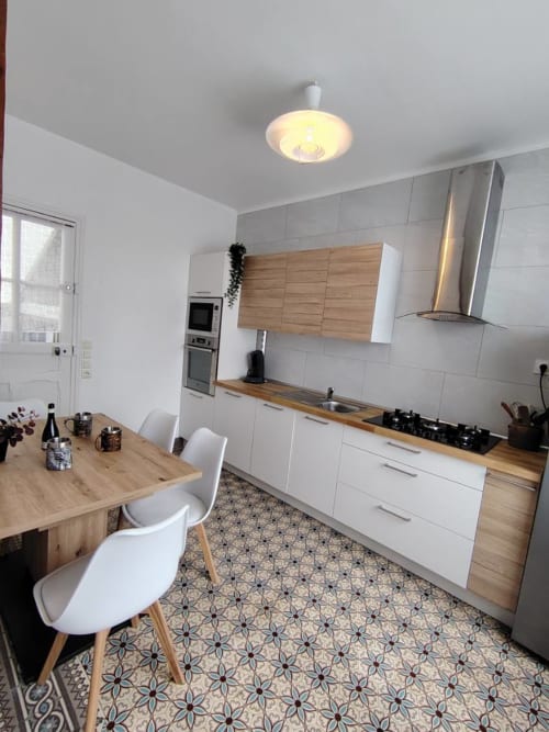 Cuisine moderne avec armoires blanches, plan de travail en bois et salle à manger du gîte Skol In Normandy à Rouen
