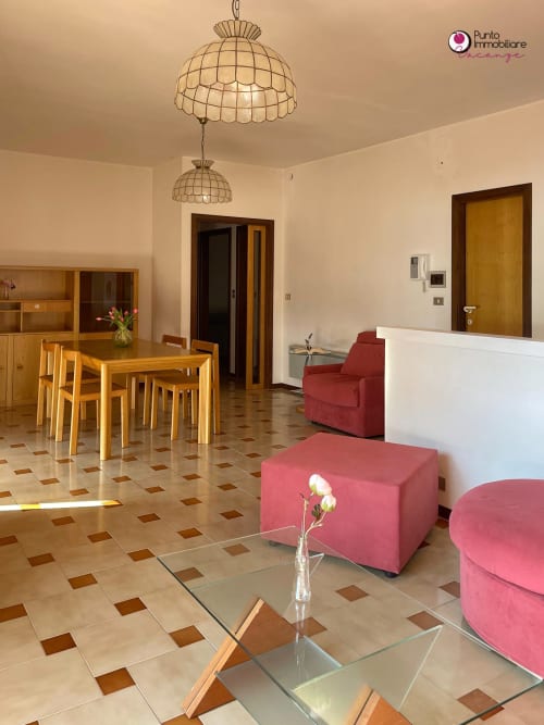 Spacious Villa Nella living area with dining table, pink seating, and terracotta tile floors in Lanciano