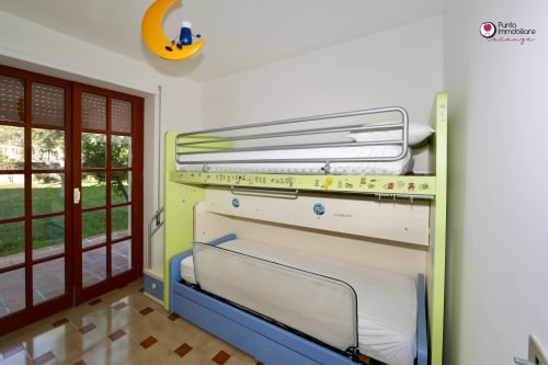 Bright children's bedroom at WelcHome Villa Nella with bunk bed, moon wall decoration, and garden view through French doors