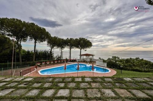 Villa Nella swimming pool with sea view in Lanciano, Italy - curved blue pool with loungers overlooking Adriatic coast