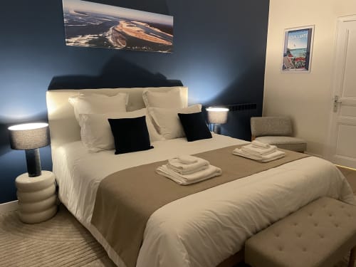 Chambre cosy à La Closerie avec literie blanche, coussins noirs, lampes de chevet et mur d'accent bleu foncé avec vue aérienne