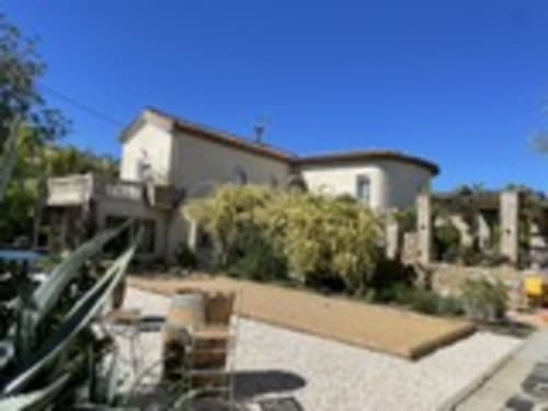 La Closerie B&B à La Redorte, France - bâtisse en pierre avec terrasse dominant le jardin sous un ciel bleu dégagé
