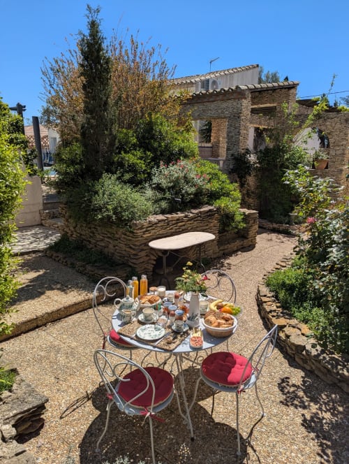 Petit-déjeuner douillet au jardin de La Closerie B&B à La Redorte, avec chaises en fer forgé, pâtisseries locales et cour en pierre