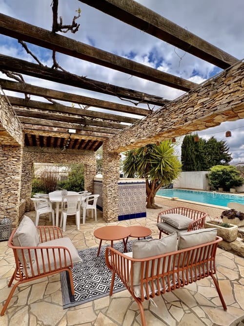 La terrasse du jardin Closerie avec pergola en pierre, mobilier de détente, piscine et palmier à La Redorte