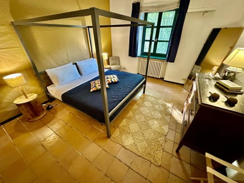 Chambre spacieuse à La Fornace B&B à Alessandria avec lit à baldaquin, coussins bleus et carrelage en terre cuite