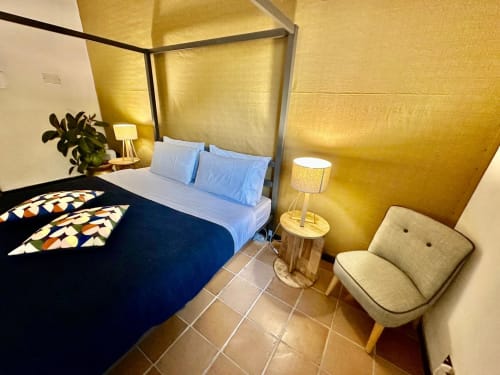 Chambre accessible à La Fornace B&B à Alessandria avec lit à baldaquin, draps bleus, murs jaunes et mobilier moderne