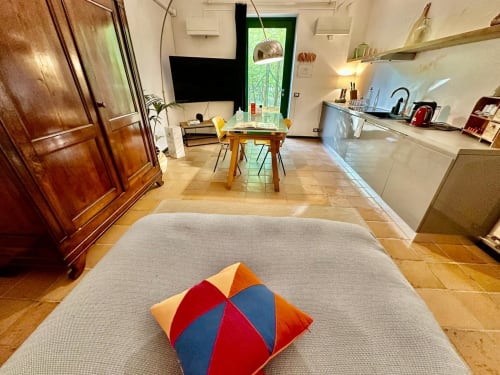 Appartement accessible à La Fornace B&B à Alessandria avec cuisine ouverte, séjour, coussin coloré sur le canapé et verdure