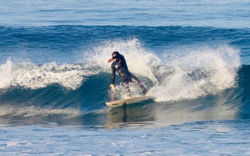 Surfeur chevauchant une vague dans les eaux bleues de l'océan près d'El Ghazouane, destination côtière du Maroc