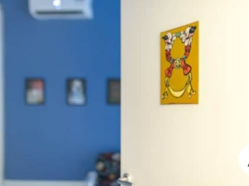 Un'opera d'arte gialla e colorata appesa alla parete color panna nella camera TreSette Toledo con parete blu di accento, Napoli