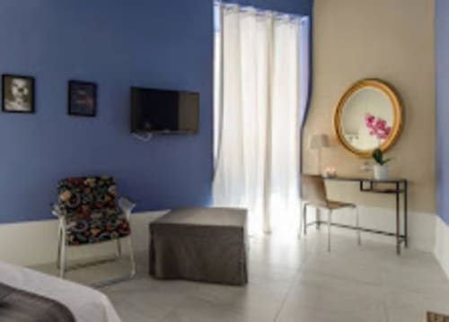 Camera moderna del TreSette Toledo a Napoli con pareti blu, scrivania con specchio, TV e vista sulla città