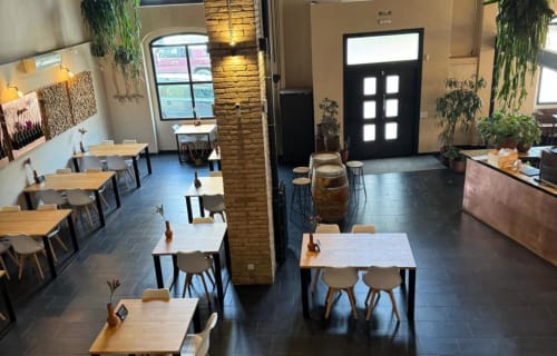 Modern dining area at B&B Wine And Cooking Penedès with wooden tables, brick column, and hanging plants