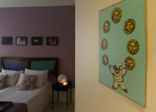 Camera da letto del TreSette Toledo BnB a Napoli con letto e giocosa arte murale di personaggio che gioca con monete d'oro su sfondo verde