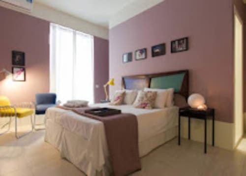 Camera moderna al TreSette Toledo di Napoli con pareti malva, letto queen, vista sulla città e arredamenti contemporanei