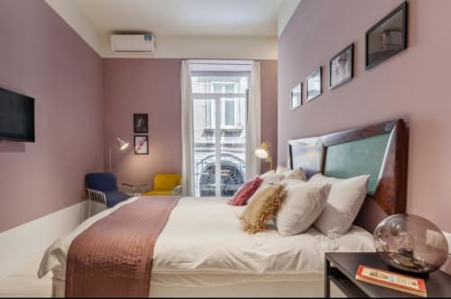 Camera da letto moderna a Napoli con pareti rosa, letto matrimoniale, balcone con vista sulla città e arredi contemporanei