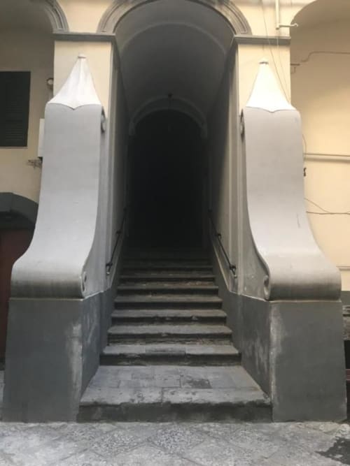 Elegante ingresso ad arco dell'appartamento TreSette Toledo a Napoli, con ringhiere bianche e ripide scalinate in pietra