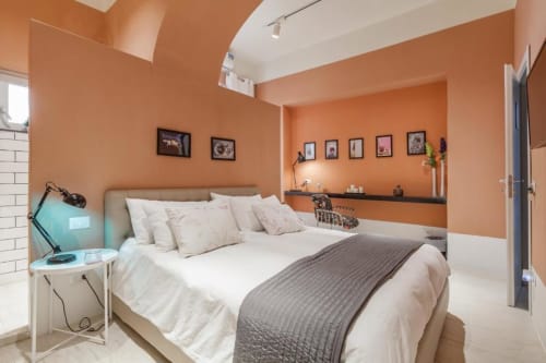 Camera da letto moderna arancione dell'appartamento TreSette Toledo Napoli con biancheria bianca, scrivania e vista sulla città