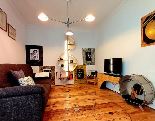 Sala de estar moderna da Casa 40th Wood Music House em Óbidos com pisos em madeira, sofá bordo, prateleira espiral central, TV e