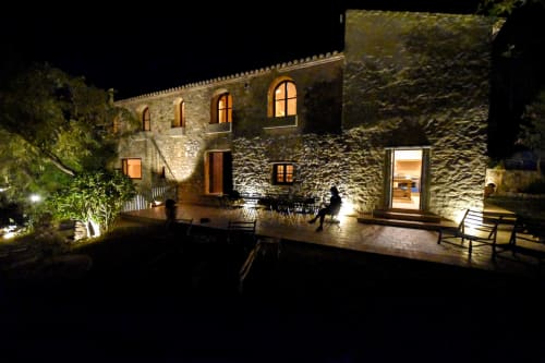 Escanda Building Solutions hotel exterior at night, illuminated stone façade with arched windows and courtyard seating in