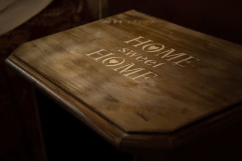 Tavolo in legno inciso con 'Home Sweet Home' presso la struttura ricettiva Casa Scola a Loano, Italia