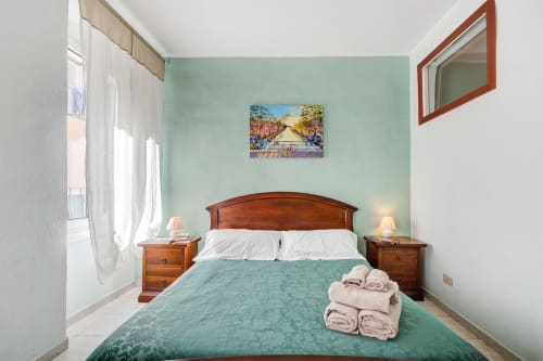 Camera luminosa di Casa Scola B&B a Loano con pareti verde menta, letto in legno e asciugamani piegati