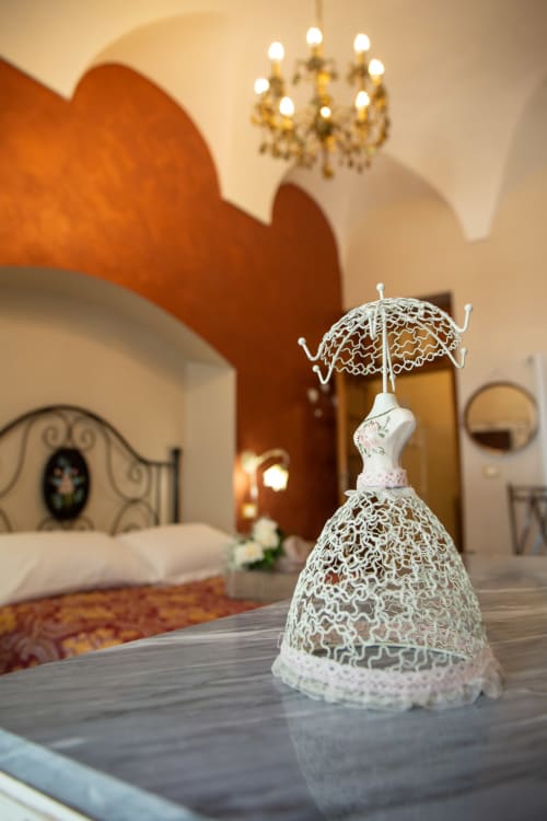 Delicato ombrello in pizzo presso la casa vacanze Casa Scola a Loano, Italia, con elegante camera da letto e lampadario sullo sfondo