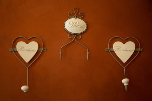 Decorazioni murali in stile francese presso la Casa Scola B&B a Loano, Italia con placche a forma di cuore e scritte 'Home'
