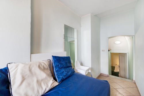 Bright bedroom at Casa Scola B&B in Loano with blue bedding, white pillows, mirror, and tile flooring
