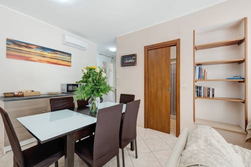 Modern dining area at Casa Scola B&B in Loano with white table, brown chairs, and wooden shelving