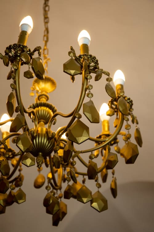 Elegant brass chandelier with crystal pendants and lit candle bulbs at Casa Scola, Loano