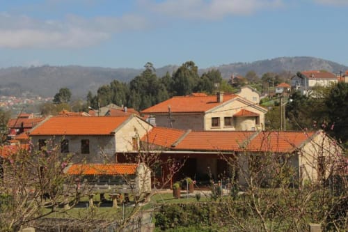 Casa Rural A Bouciña, hotel rural con tejados de barro y edificios de piedra rodeados de árboles en Hío, Galicia