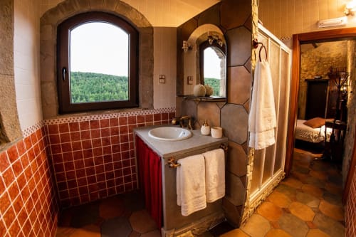 Baño con vistas al bosque junto a un dormitorio de piedra