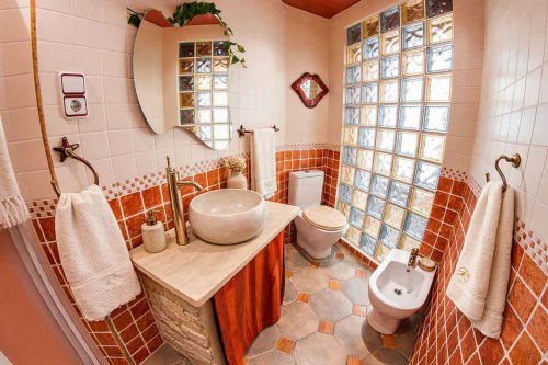 Baño luminoso con acabados cálidos y ducha de cristal translúcido